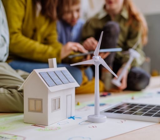 Close-up of a house model with solar system and wind turbine during a school lesson.
